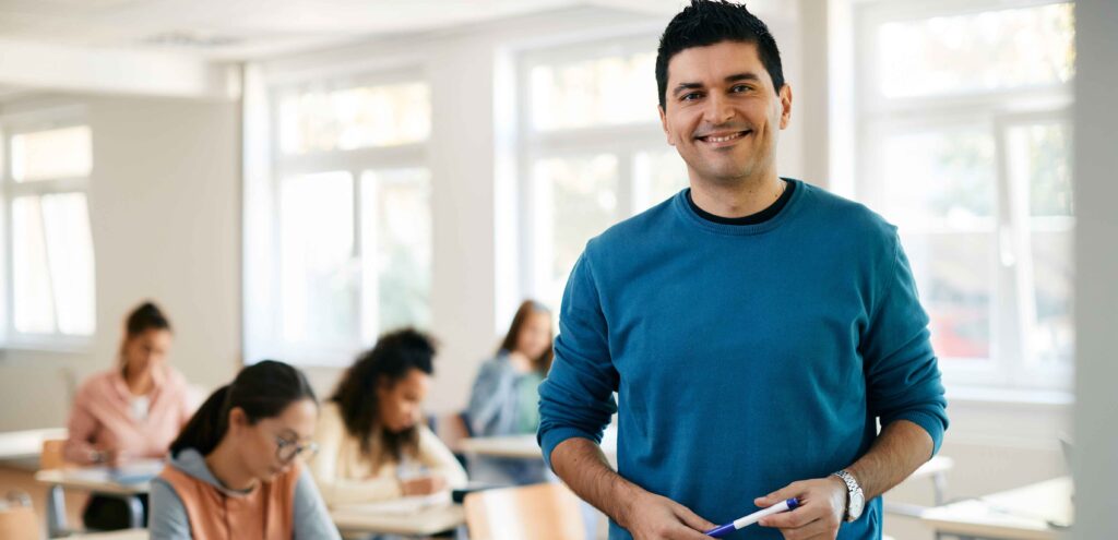 teacher posing and smiling while standing in front of a class
