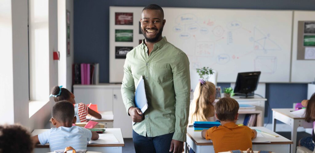 teacher standing in aisle of classroom smiling for a picture