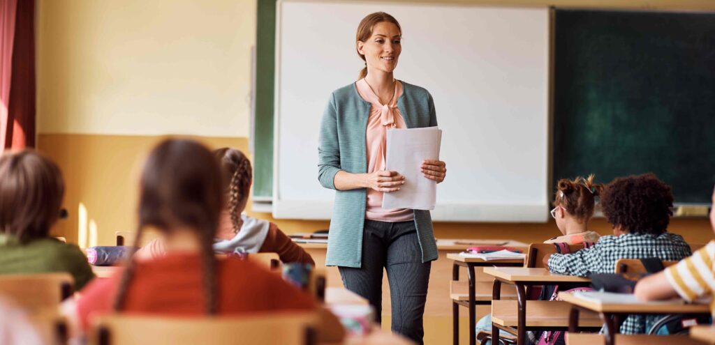 teacher standing at the front of class teaching her students