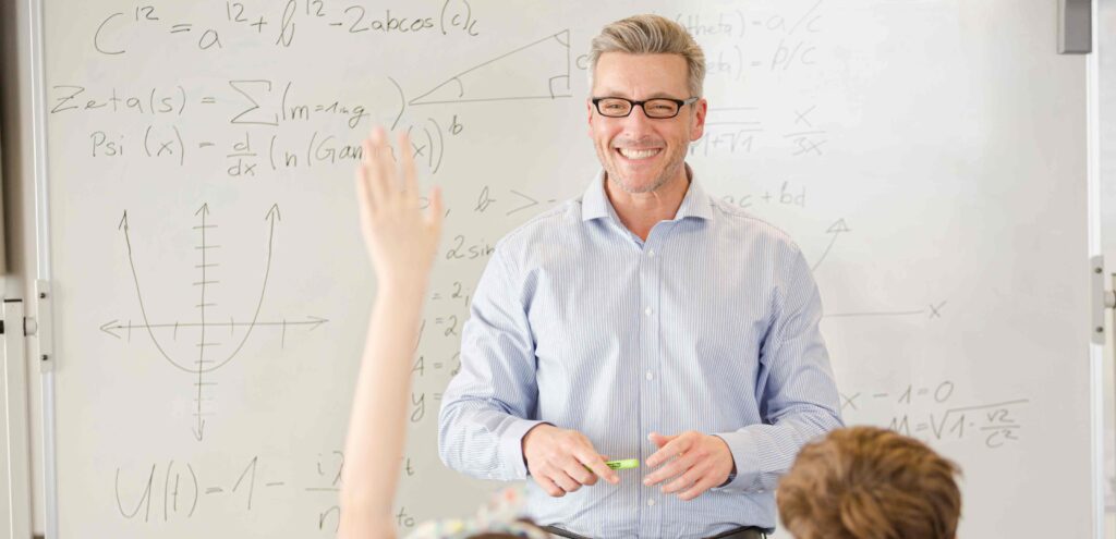 math teacher standing at front of class teaching