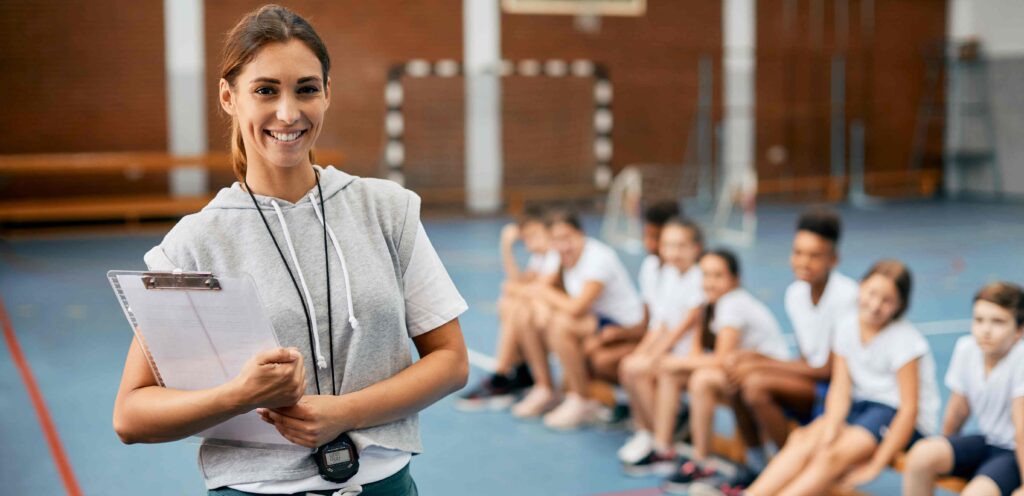 pe teacher smiling with her class behind her 